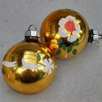 guldfarvet retro glasjulekugle med hvide og orange blomster og lidt grønt gammelt julestads